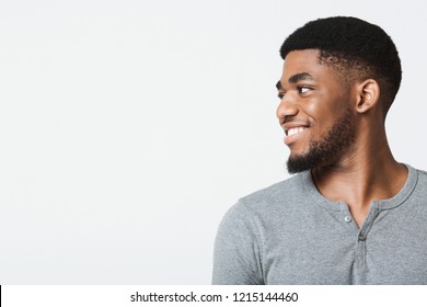 Half-turned smiling african-american man looking at copy space, white studio background