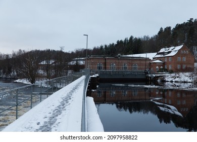 Oskarström, Halland, Sweden - December 11, 2021: Winter Image Of A Small Water Power Plant On The Nissan River. There Is A Bridge Over The River And Old Building Of A Plant. 