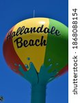 Hallandale Beach text symbol on exterior of colorful beach ball water storage tower landmark near local fire station on a sunny summer day with a clear blue sky