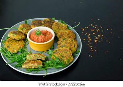 Halloumi Carrot Fritters With Roasted Red Pepper And Cashew Dip With Chili Flakes On A Black Table, Top View 