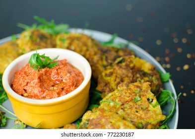 Halloumi Carrot Fritters With Roasted Red Pepper And Cashew Dip With Chili Flakes On A Black Table, Close Up