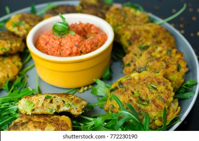 Halloumi Carrot Fritters With Roasted Red Pepper And Cashew Dip With Chili Flakes On A Black Table, Close Up