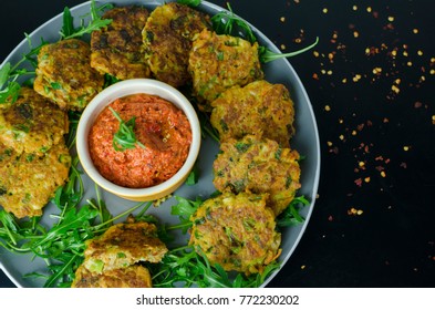 Halloumi Carrot Fritters With Roasted Red Pepper And Cashew Dip With Chili Flakes On A Black Table, Top View 