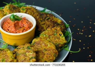 Halloumi Carrot Fritters With Roasted Red Pepper And Cashew Dip With Chili Flakes On A Black Table, Top View 