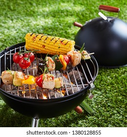 Halloumi Or Tofu Vegetarian Kebabs Grilling On An Outdoor Portable BBQ With Corn On The Cob On A Green Lawn In A Concept Of Healthy Outdoors Summer Lifestyle And Vegan Or Vegetarian Cuisine