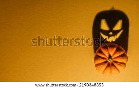 Halloween background concept. Jack O pumpkin angry face shadow. Spooky smiling shadow of an orange pumpkin lantern top view close up, Halloween party design