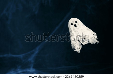 Halloween background with ghost and spider web. Ghost made of gauze on a dark blue background with copy space. Creative DIY Halloween decor.