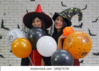 halloween background of portrait of two asian women in witches costume with balloon for halloween night party - Shutterstock ID 1838275750