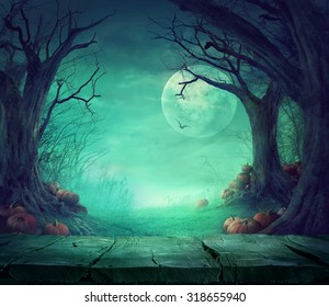 Halloween background. Spooky forest with dead trees and pumpkins and wooden table. Wood table. Halloween design with pumpkins