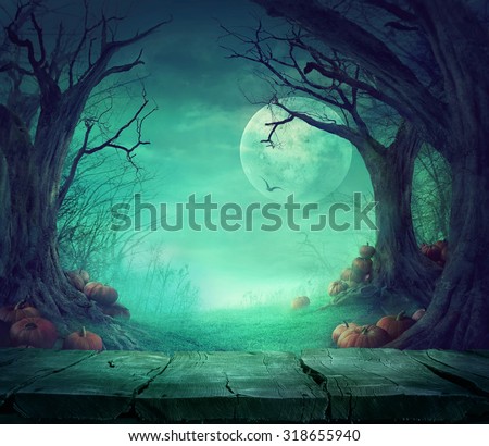 Halloween background. Spooky forest with dead trees and pumpkins and wooden table. Wood table. Halloween design with pumpkins