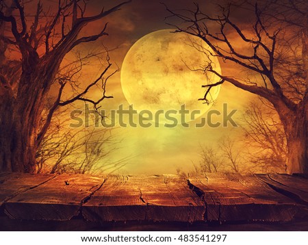 Halloween background. Spooky forest with full moon and wooden table