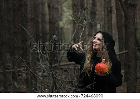 Halloween. beautiful witch girl in a black dress in the forest