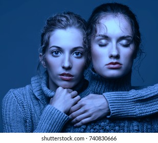 Halloween beauty portrait of two young women in gray sweaters on grey studio background. Beautiful girls stretching hands forward in embrace. Female friendship concept. One girl with eyes closed.
