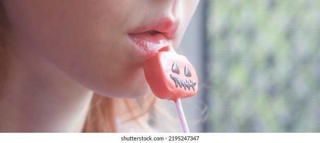 Halloween Cake Pop In Front Of A Caucasian Person's Mouth