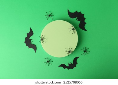 Halloween celebration. Podium, decorative bats and spiders on green background, flat lay. Space for text - Powered by Shutterstock