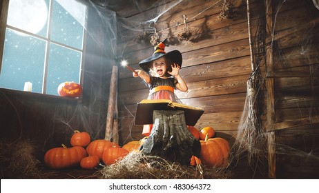 Halloween. Child Little Witch With Magic Wand And Reading A Magical Book Of Spells In The Old Hut