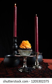 Halloween Chocolate Cupcake With Orange Frosting, Cauldrons, Spiders, And Candles