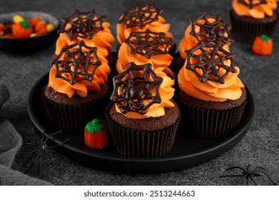 Halloween chocolate cupcakes with orange frosting and chocolate spider web on a dark background. Festive dessert. Funny food idea. Copy space - Powered by Shutterstock