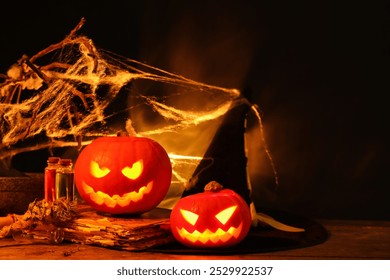 Halloween composition with jack-o-lanterns, witch hat, web and potions on wooden table