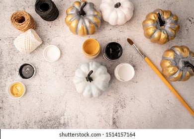 Halloween Concept. Halloween DIY Crafts. White And Gold Painted Pumpkin On The Table With Pains Top View Flat Lay