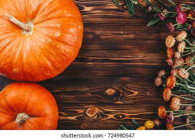 Halloween concept with fresh pumpkins and flowers on the wooden table. Trick or Treat view from above