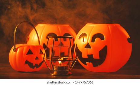 Halloween concept - Orange plastic pumpkin lantern with laugh face on a dark wooden table with smoke around the background, trick or treat, close up. - Powered by Shutterstock