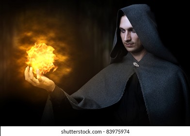 Halloween Concept. Powerful Male Witch Or Wizard With Fireball In Hands. Ball From Fire Burns