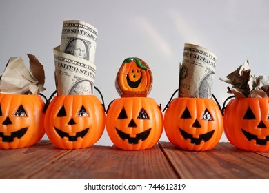 Halloween Concept, Smile Face Pumpkins With Dollar Money, Doll And Crumpled Paper On Old Vintage Wood In White Background 