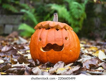 Halloween Cute Curved Orange Pumpkin With Funny Moustache Face In The Autumn Garden. Treat Or Trick Tradition. Autumn Crafts Kids Ideas. Copy Space.