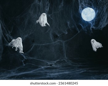 Halloween dark background with ghosts, glowing moon and a spider web with copy space. Image for montage or display your products. Ghosts made of gauze and starch. Halloween decor. - Powered by Shutterstock