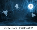 Halloween dark blue background with cobwebs, ghosts and a glowing moon. Image for montage or display your products with a copy space.