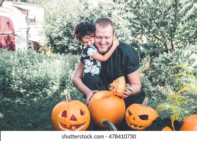 Halloween. Daughter Hugging Father. Man Cuts A Lid From A Pumpkin As He Prepares A Jack-o-lantern. Decoration For Party. Toned Photo. Family.