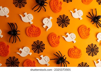 Halloween decor pattern black spider, cobweb, pumpkin, ghost on orange background flat lay