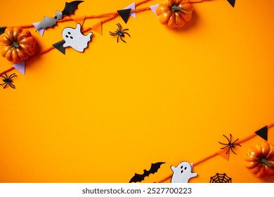 Halloween decor with pumpkins, bunting garland, ghosts, and spiders on vibrant orange background - Powered by Shutterstock