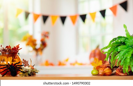 Halloween Decoration. Pumpkin Lantern And Autumn Leaf In Home Interior Design. Festive Decorated Table Family Traditional Celebration. Fall Holidays. Window With Banner And Sun Light In Living Room.