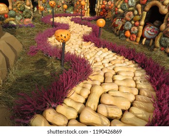 Halloween Decorations, Jack O' Lanterns And Fairy Tale Characters. Yellow Brick Road In The Oz Country Made From Pumpkins And Flowers, Autumn Harvest Holiday