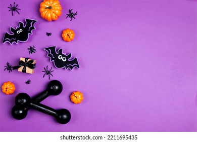 Вumbbells with Halloween decorations on purple. Top view Halloween fitness composition with copy space. - Shutterstock ID 2211695435