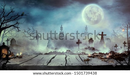 Halloween design with wooden table and graveyard. Spooky cemetery with tombs