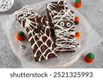 Halloween dessert. Chocolate brownie decorated with chocolate icing in the shape of a mummy and with a spider on a web. Top view, copy space