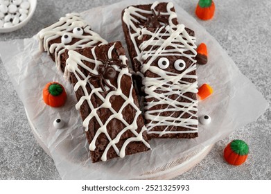 Halloween dessert. Chocolate brownie decorated with chocolate icing in the shape of a mummy and with a spider on a web. Top view, copy space - Powered by Shutterstock