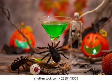 Halloween Drinks Green Cocktail Martini For Party Hand In Glove Holds Glass On Festive Background.