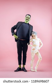 Halloween Family. Happy Father And Children Girl In Halloween Costume And Makeup. Bloody Theme: The Crazy Maniak Faces On Pink Studio Background