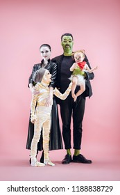 Halloween Family. Happy Father, Mother And Children Girls In Halloween Costume And Makeup. Bloody Theme: The Crazy Maniak Faces On Pink Studio Background