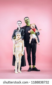 Halloween Family. Happy Father, Mother And Children Girls In Halloween Costume And Makeup. Bloody Theme: The Crazy Maniak Faces On Pink Studio Background