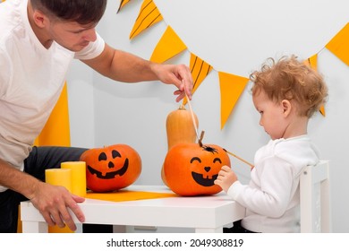 Halloween Family Indoor Activity, Pumpkin Painting Process. Cute Child Drawing Scary Face. Holiday Preparation And Handmade Party Decor