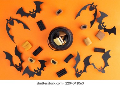 Halloween flat lay composition with candies, bats  and In the center is a small cauldron with sweets on orange background. Happy halloween banner mockup. - Shutterstock ID 2204341063
