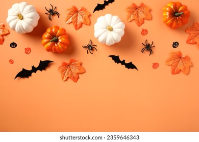Halloween flat lay composition with pumpkins, spiders, bats, maple leaves on pastel orange background. - Shutterstock ID 2359646343
