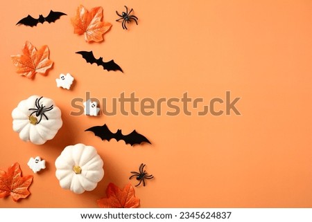 Halloween flat lay composition with pumpkins, spiders, bats, maple leaves on orange background. Happy Halloween holiday concept. Flat lay, top view, copy space.
