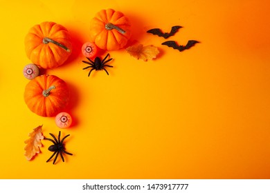Halloween flat lay top view scene with pumpkins and spiders on orange background with copy space
