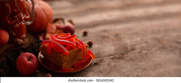 Halloween Food Still Life Abstract Background With Pumpkins, Apples, Cake, Gummy Worms, Skull Red Drink And Candles